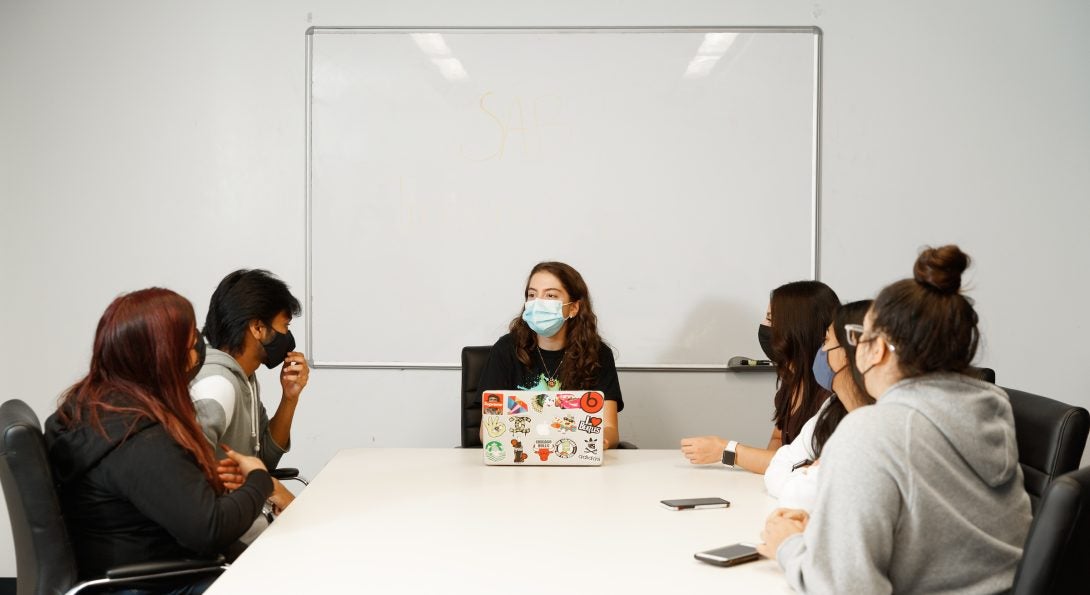 students sitting around a white conference room table facing SAB committee chair student